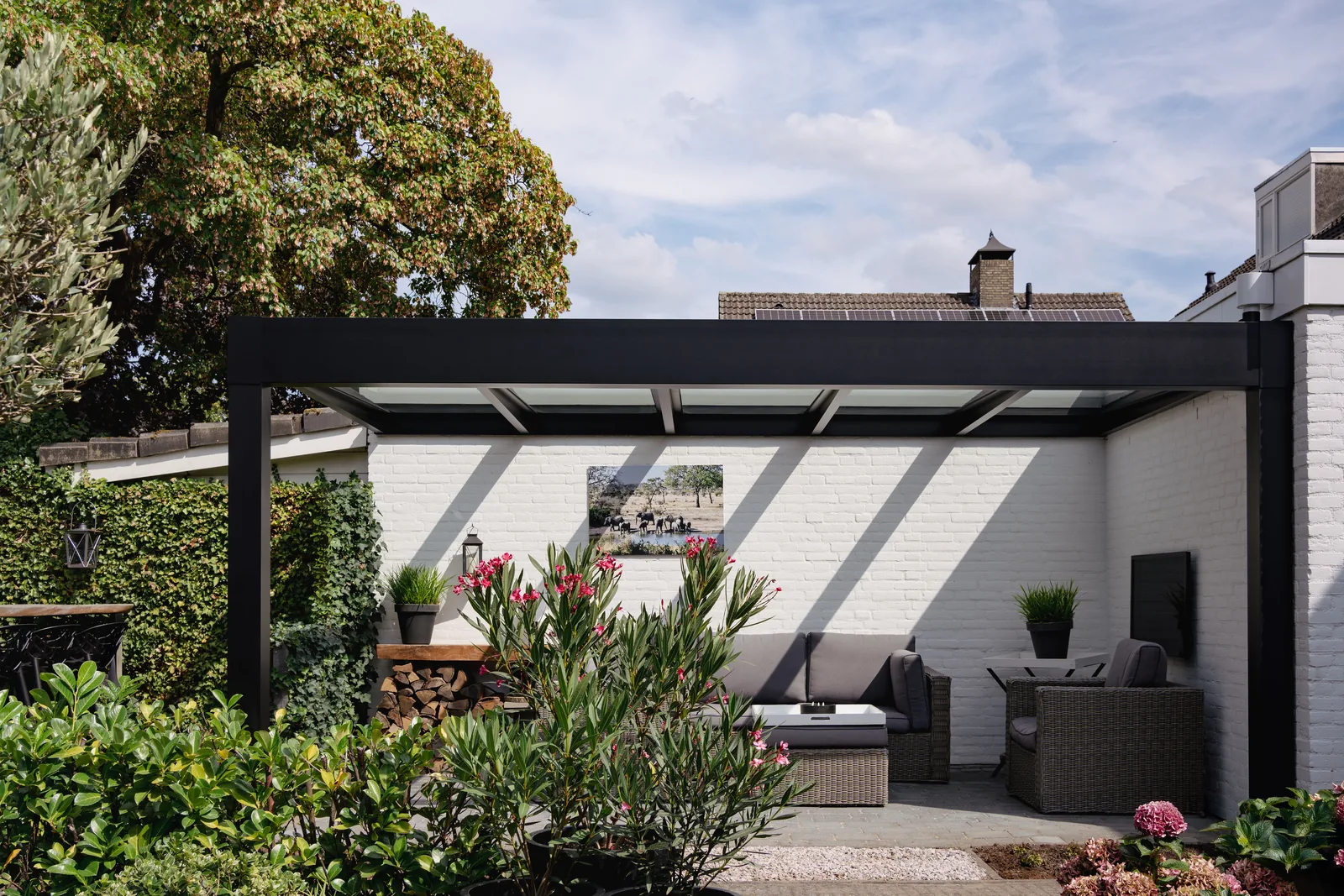 Kubische Terrassenüberdachung Trebbiano in Schwarz mit Glasdach an einer weißen Hauswand